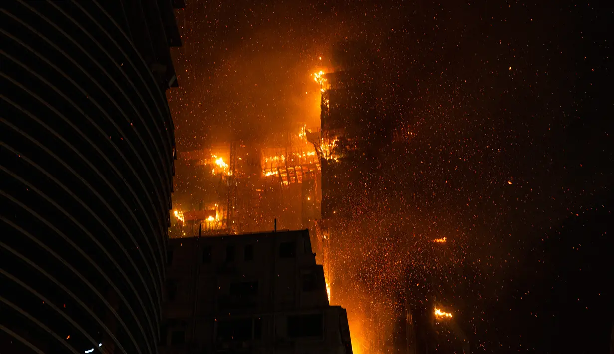 Kebakaran melanda lokasi konstruksi di Hong Kong, Jumat (3/3/2023). Lebih dari 100 warga yang tinggal dekat gedung dievakuasi imbas dari asap yang muncul akibat kebakaran. (AP Photo/Louise Delmotte)
