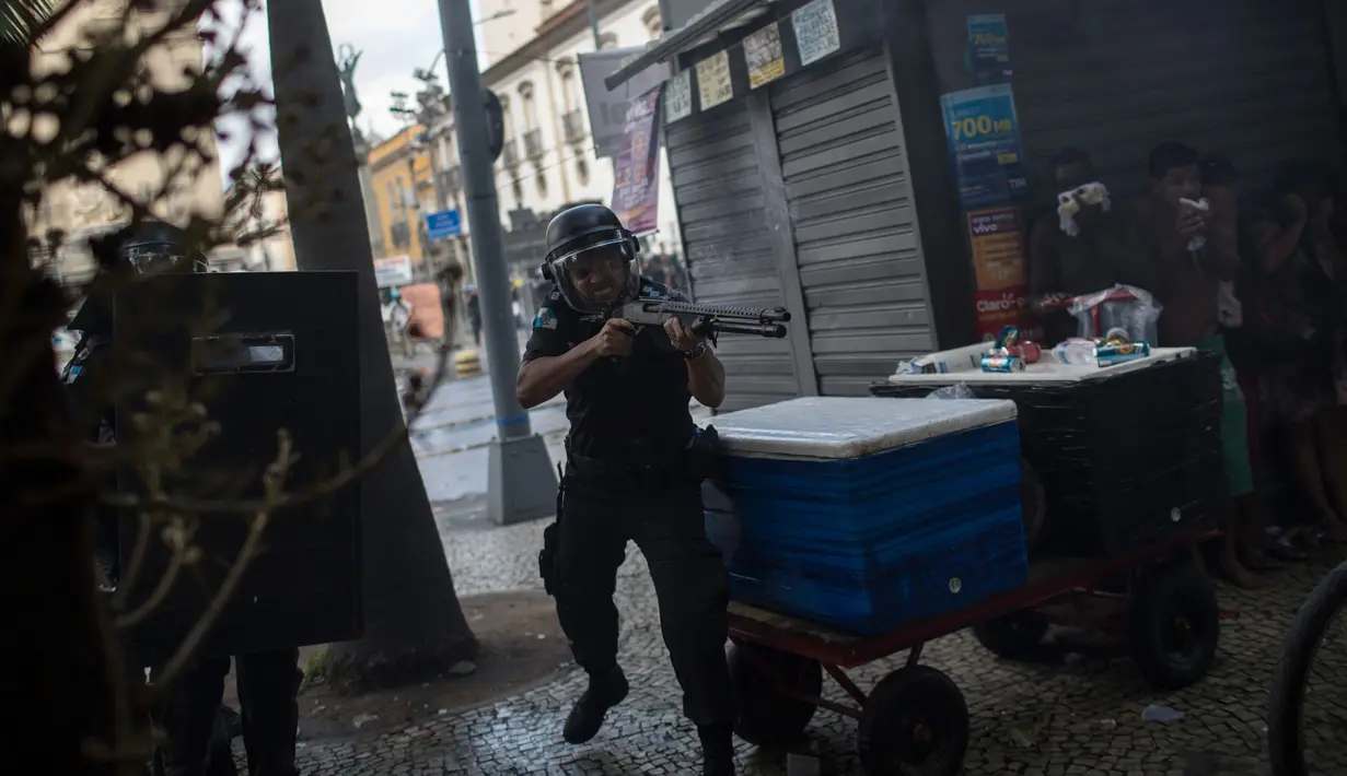 Polisi menggunakan senjata menghalau para pengunjuk rasa saat bentrokan memprotes rencana pembatasan belanja publik di Rio de Janeiro, Brasil, (9/2). (AP Photo/Felipe Dana)
