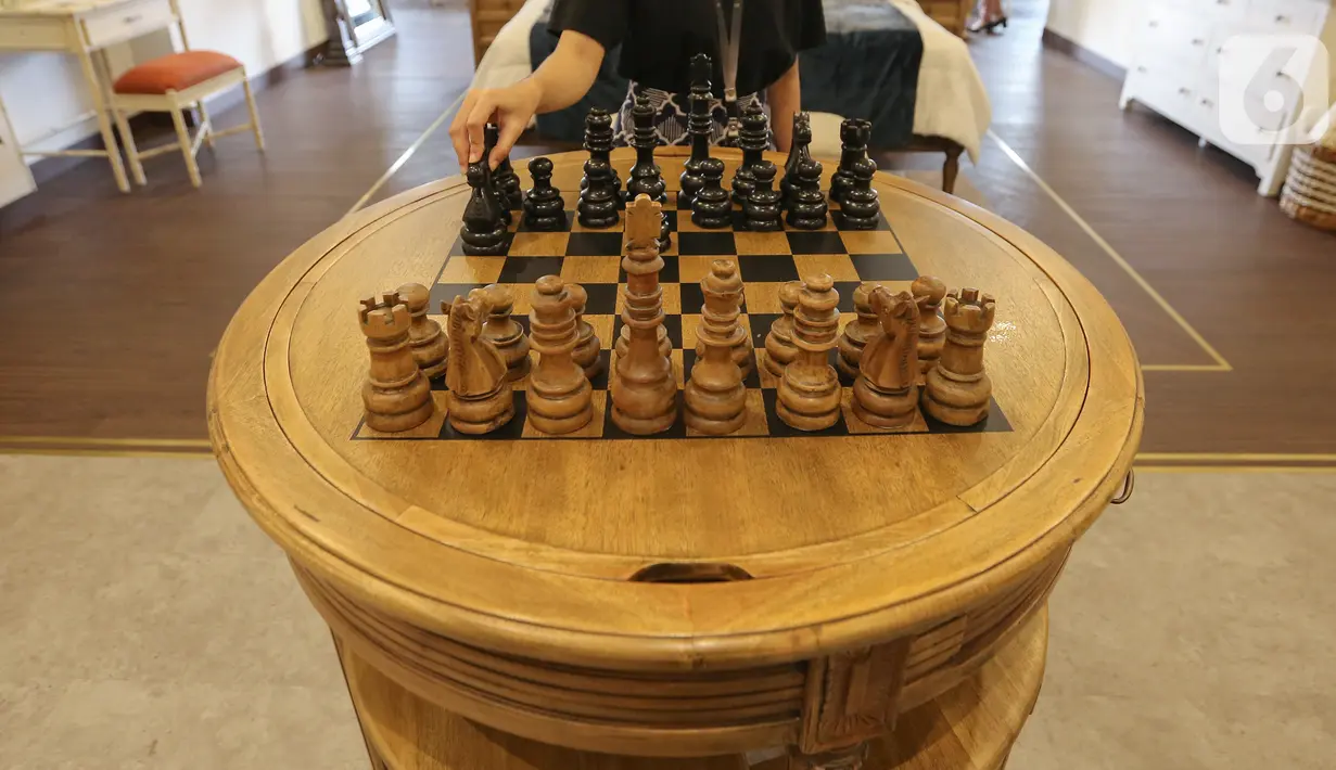 Pengunjung memainkan bidak catur dari jenis kayu mahoni di Bramble Furniture, Kemang Timur, Jakarta, Selasa (28/1/2020). Furniture yang mengusung interior dengan nuansa homey mulai dari tema ruang keluarga, ruang makan, hingga set up apartemen juga menggandeng Ars. app. (Liputan6.com/Fery Pradolo)