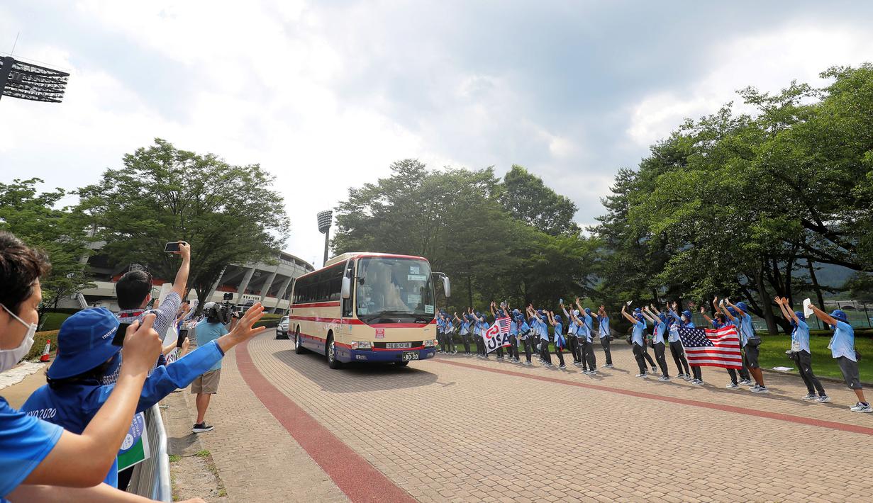 Sejumlah relawan bersorak saat bus yang membawa pemain softball Ameria Serikat meninggalkan Stadion Bisbol Fukushima Azuma setelah pertandingan putaran pembukaan softball Olimpiade Tokyo 2020 antara Italia melawan Amerika Serikat di Fukushima, Jepang, pada 21 Juli 2021. (AFP/Kazuhiro Fujihara)