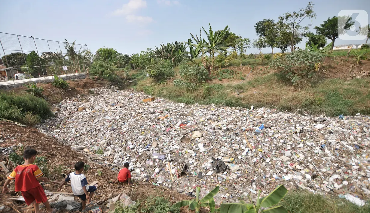 Anak-anak bermain dekat tumpukan sampah yang memenuhi Kali Jambe, Desa Satria Jaya, Tambun Utara, Bekasi, Jawa Barat, Kamis (31/10/2019). Sampah tersebut merupakan limbah rumah tangga yang terdiri dari styrofoam, plastik, batang pohon, hingga kasur. (merdeka.com/Iqbal Nugroho)