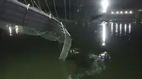 Tim penyelamat di kapal mencari di sungai Machchu di sebelah jembatan kabel yang runtuh di distrik Morbi, negara bagian Gujarat barat, India, Minggu, 30 Oktober 2022. Puluhan dikhawatirkan tewas dan beberapa terluka dalam kecelakaan itu.
