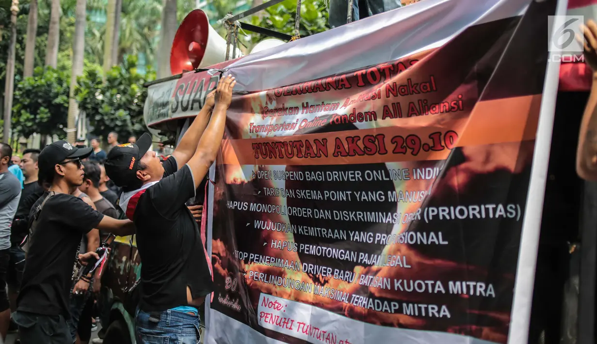 Pengemudi online membentangkan spanduk saat menggelar aksi di kantor pusat Grab, Jakarta, Senin (29/10). Mereka menuntut penentuan tarif dan skema yang manusiawi, serta monopoli dan diskriminasi order (order prioritas). (Liputan6.com/Faizal Fanani)