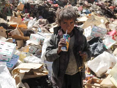 Seorang bocah laki-laki minum jus kadaluwarsa dari tumpukan sampah di sebuah tempat pembuangan akhir (TPA) di pinggiran Sanaa, Yaman, Rabu (16/11). Setiap hari para bocah di daerah itu mengumpulkan sampah untuk didaur ulang. (REUTERS/Mohamed al-Sayaghi)