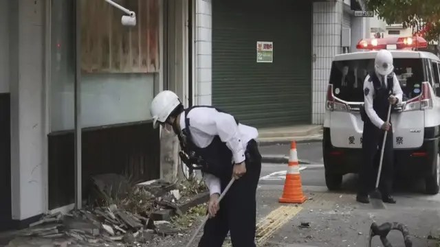 Petugas polisi membersihkan puing-puing gempa di Uwajima, prefektur Ehime, Jepang bagian barat Kamis, 18 April 2024. (Kyodo News/AP)