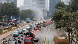 Petugas gabungan menyemprotkan air di kawasan jalan utama Jakarta yang terdampak sebaran abu vulkanik Gunung Anak Krakatau, sebagai langkah mengurangi partikel debu di permukaan jalan. (KLY/Budy Santoso)