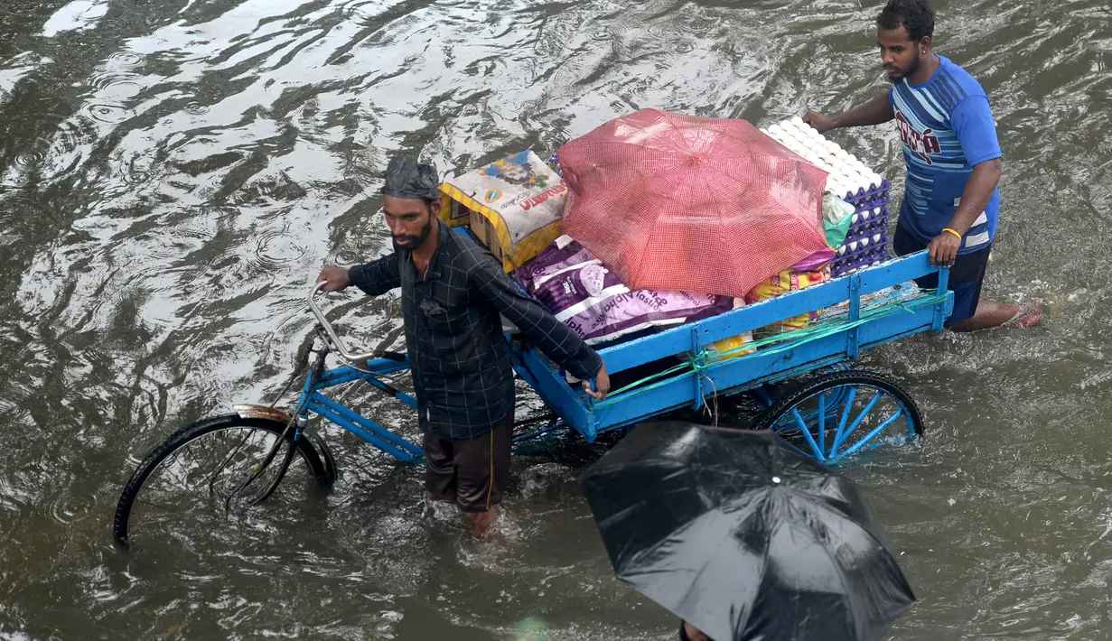 Orang-orang mengarungi jalan yang banjir setelah hujan lebat di Chennai, India (8/11/2021). Departemen Meteorologi India (IMD) memperkirakan lebih banyak curah hujan dalam beberapa hari mendatang. (AFP/Arun Sankar)