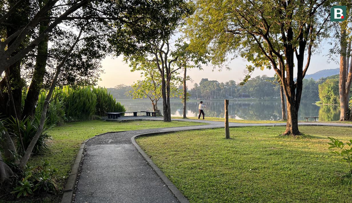 Seorang warga berolahraga di bawah rindangnnya pepohonan di tepi Danau Angkaew di Chiang Mai, Thailand, Senin (8/12/2025). (Bola.com/Bagaskara Lazuardi)