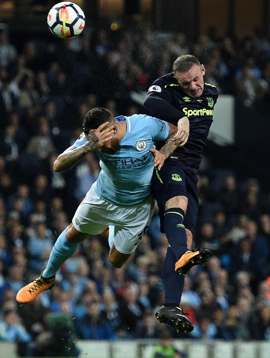 Striker Everton, Wayne Rooney, duel udara dengan bek Manchester City, Nicolas Otamendi, pada laga Premier League di Stadion Etihad, Selasa (22/8/2017). Wayne Rooney berhasil mencetak gol ke 200 di ajang Premier League. (AFP/Oli Scarff)