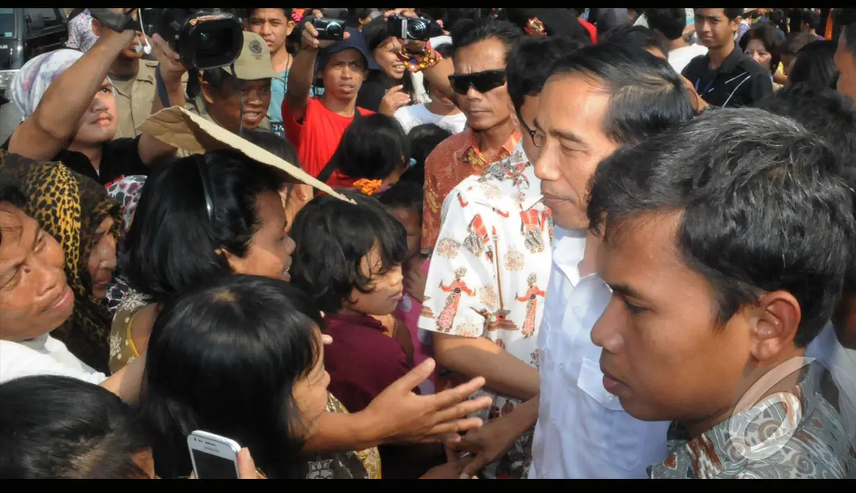 Jokowi menyempatkan diri untuk membagian uang sendiri kepada warga yang antre di tengah teriknya matahari dan debu di pinggiran waduk, Jakarta, Kamis (24/7/2014) (Liputan6.com/Herman Zakharia)