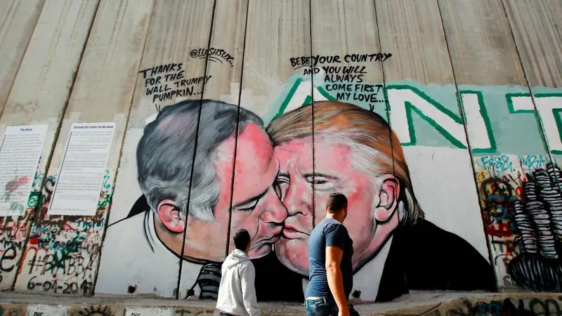 Mural Presiden AS Donald Trump berciuman dengan PM Israel Benjamin Netanyahu di tembok pembatas di Tepi Barat Yerusalem. Mural tersebut karya seniman Australia, Lushux (AFP/Musa Al Shaer)