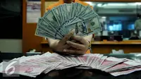 Petugas memperlihatkan uang pecahan US$100 dan rupiah di pusat penukaran uang, Jakarta, , Rabu (12/8/2015). Reshuffle kabinet pemerintahan Jokowi-JK, nilai Rupiah terahadap Dollar AS hingga siang ini menembus Rp 13.849. (Liputan6.com/Johan Tallo)