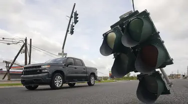 Kendaraan melintasi lampu lalu lintas yang tergantung di kabel setelah terjangan Badai Ida di LaPlace, Louisiana, Senin (30/8/2021). Badai Ida ini sebagai salah satu badai paling kuat yang pernah melanda Amerika Serikat. (AP Photo/Steve Helber)