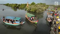 Perahu wisata melintasi kerumunan wisatawan yang berjalan di atas Jembatan Cinta di Wisata Mangrove, Tarumajaya, Bekasi, Minggu (30/12). Wisata tersebut berbatasan langsung dengan kawasan Marunda Jakarta Utara. (merdeka.com/Arie Basuki)