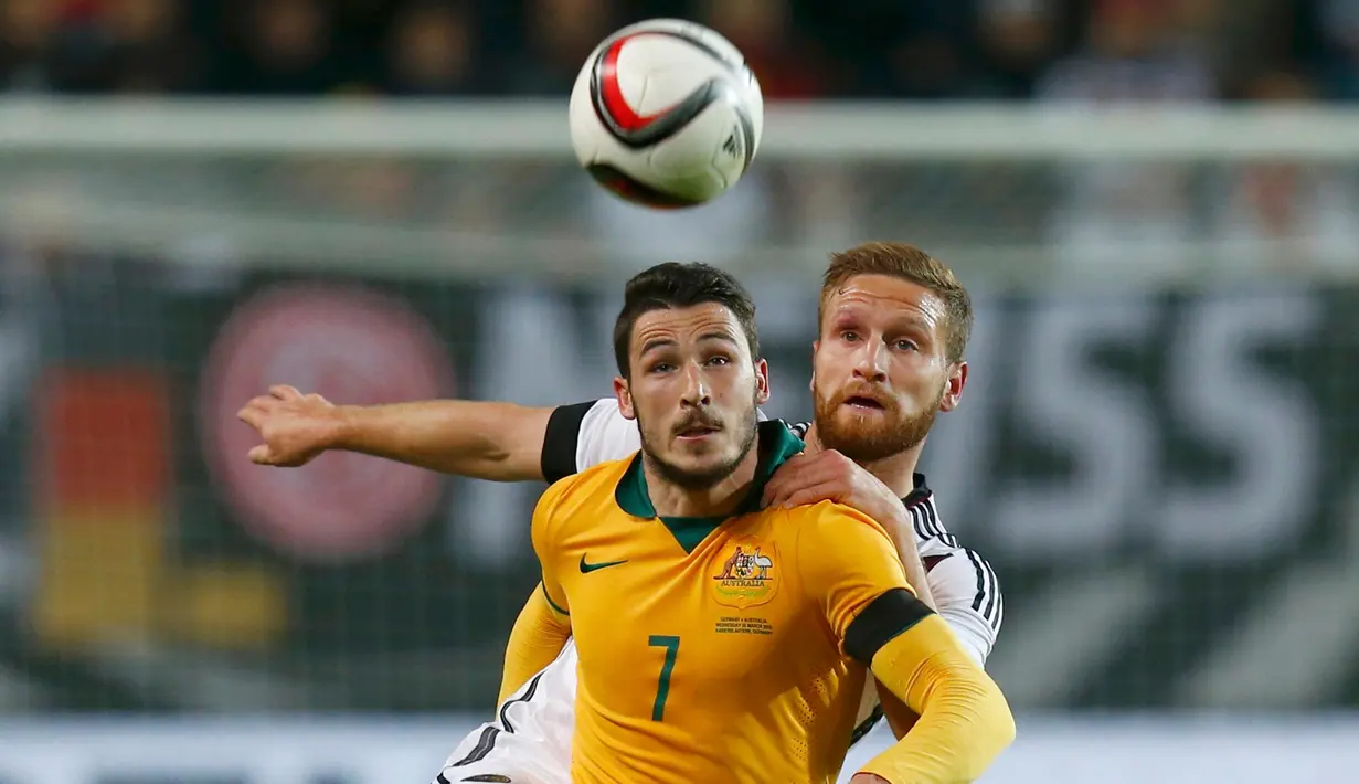 Penyerang Australia, Mathew Leckie berebut bola udara dengan bek Jerman Shkodran Mustafi saat laga persahabatan di Stadion Fritz-Walter, Kamis (26/3/2015). Jerman bermain Imbang 2-2 atas Australia. (REUTERS/Ralph Orlowski)