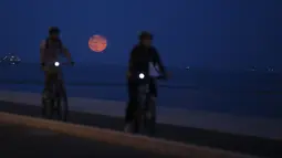 Dua orang pria bermain sepeda dengan latar belakang supermoon, di Lisbon, Portugal, Selasa (9/9/14). (REUTERS/Rafael Marchante)