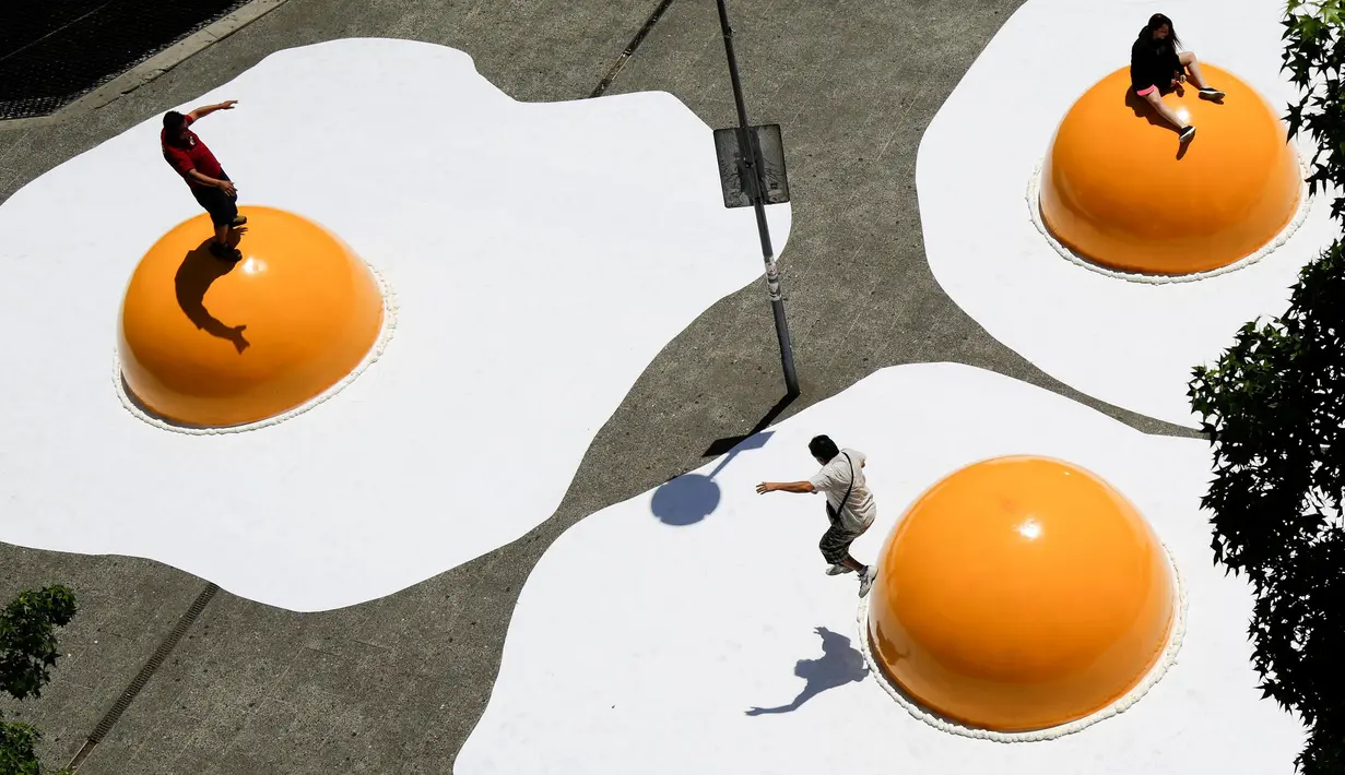 Sejumlah warga bermain di atas telur ceplok raksasa yang diletakkan di pusat kota Santiago, Chile, 8 November 2016. Telur mata sapi raksasa ini merupakan bagian dari festival seni Hecho en Casa. (REUTERS / Pablo Sanhueza)