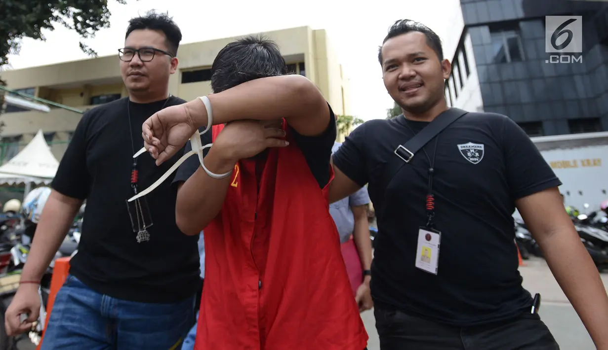 Tersangka berinisial MIK penyebar hoax surat suara tercoblos yang berprofesi sebagai guru di Cilegon digiring petugas di Polda Metro Jaya, Jakarta, Jumat (11/1). Screenshot posting-an di Twitter MIK menjadi barang bukti polisi. (Merdeka.com/Imam Buhori)