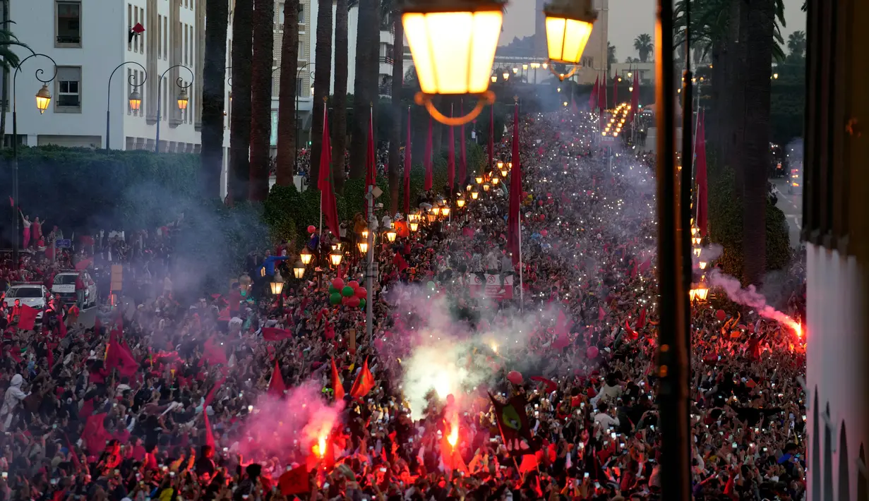 Suporter menyalakan suar saat parade Timnas Maroko di Rabat, Maroko, 20 Desember 2022. Timnas Maroko mendapat sambutan hangat di negaranya setelah berhasil meraih juara keempat Piala Dunia 2022. (AP Photo/Mosa'ab Elshamy)