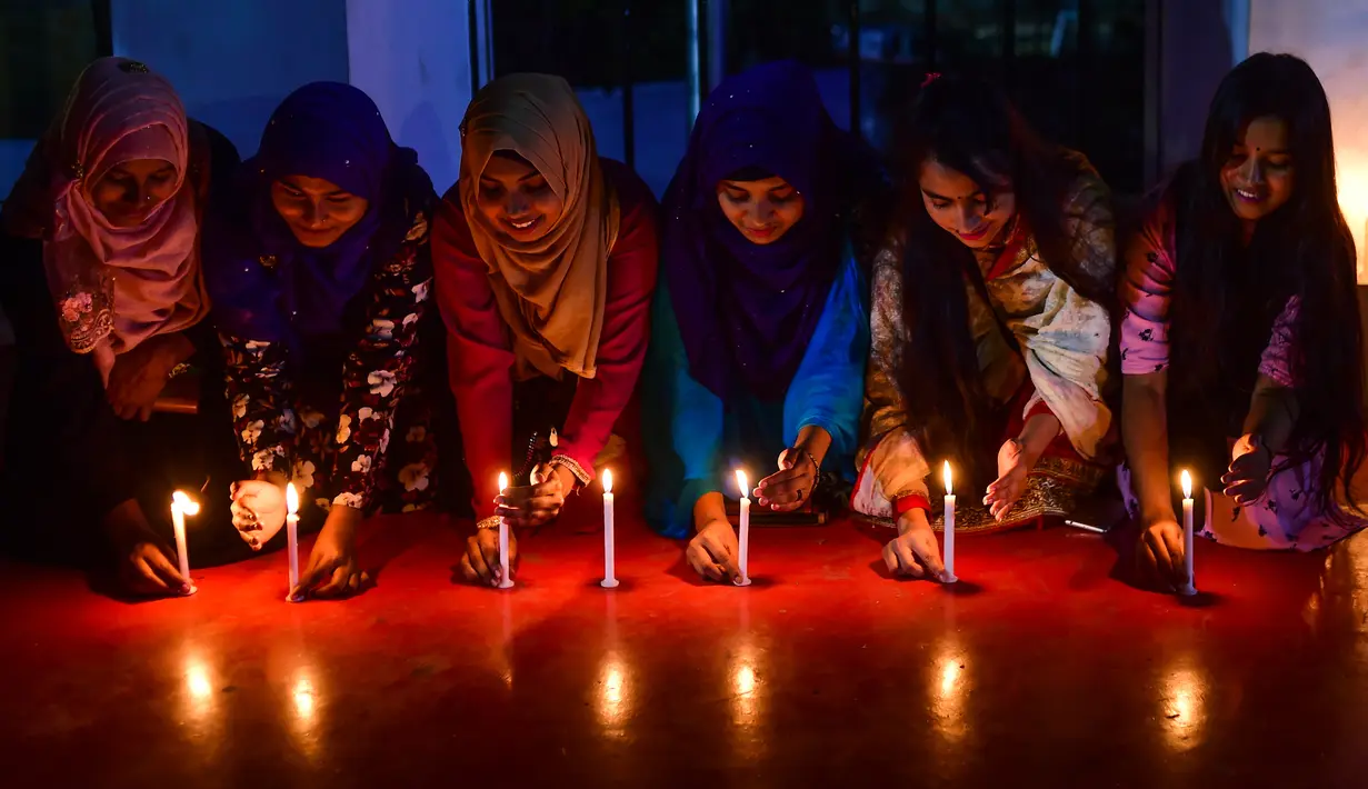 Sejumlah wanita Bangladesh meletakkan lilin saat memperingati Hari Perempuan Internasional di Dhaka (7/3). Hari Perempuan Internasional secara resmi dijadikan sebagai hari libur nasional di Soviet Rusia pada tahun 1917. (AFP Photo/Munir Uzzaman)