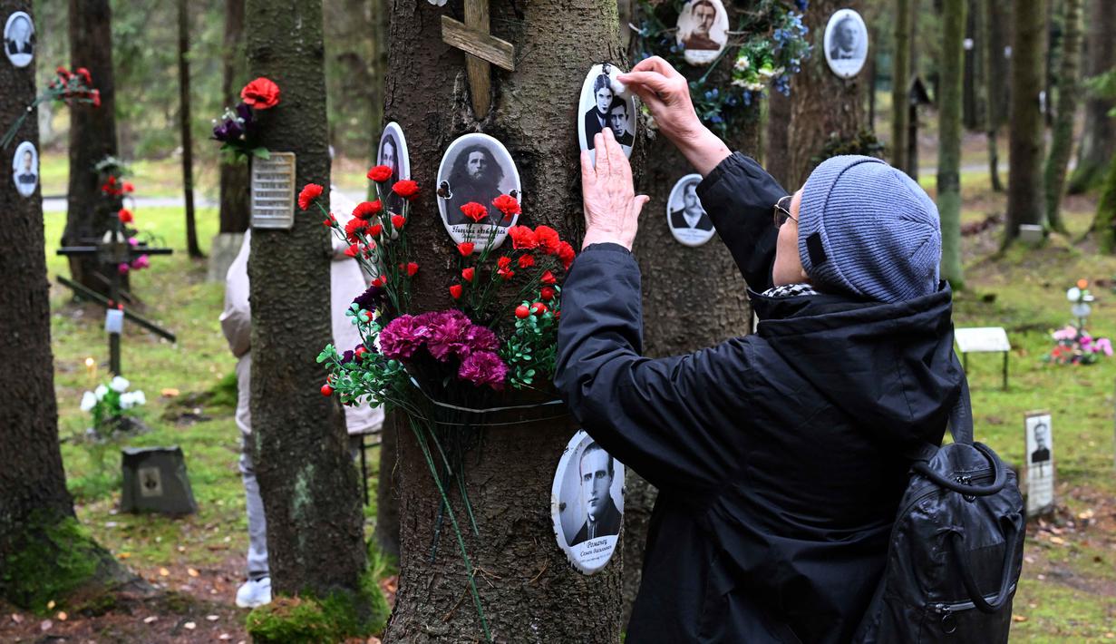 Orang-orang mengunjungi tugu peringatan tempat para korban rezim diktator Soviet Joseph Stalin dimakamkan di hutan di pinggiran Saint Petersburg pada 30 Oktober 2025. Rusia memperingati Hari Korban Represi Politik untuk mengenang ribuan korban yang gugur dalam represi rezim Komunis Soviet. (Olga MALTSEVA/AFP)