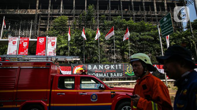 Petugas pemadam kebakaran melintas di depan gedung utama Kejaksaan Agung yang terbakar di Jakarta, Minggu (23/8/2020). Kebakaran yang berawal sejak Sabtu (22/8) malam itu, baru bisa dikuasai pagi ini, Minggu (23/8). (Liputan6.com/Faizal Fanani)