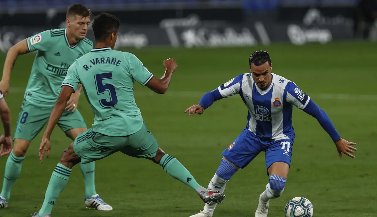 Pemain Espanyol Raul de Tomas (kanan) menggiring bola melewati pemain Real Madrid Raphael Varane pada pertandingan La Liga Spanyol di Stadion Cornella-El Prat, Barcelona, Spanyol, Minggu (28/6/2020). Real Madrid menang 1-0 dan menggeser Barcelona dari puncak klasemen. (AP Photo/Joan Monfort)