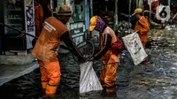 Petugas PPSU membersihkan sampah saat terjadi banjir rob di Pelabuhan Kali Adem, Muara Angke, Jakarta, Selasa (9/11/2021). Walau terendam banjir rob, petugas PPSU tetap sigap bersihkan sampah yang mengambang terbawa air laut. (Liputan6.com/Faizal Fanani)