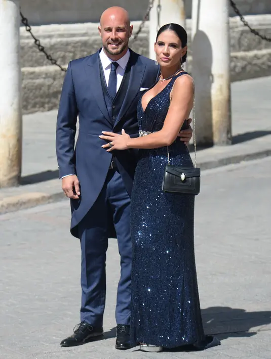 Kiper Spanyol Pepe Mena dan istrinya Yolanda Ruiz berpose saat tiba di gereja menghadiri upacara pernikahan bek Sergio Ramos dan Pilar Rubio di Katedral Seville, Spanyol (15/6/2019). (AFP Photo/Cristina Quicler)