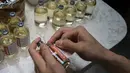 Seorang karyawan meletakkan label pada botol minuman Sinosovr, minuman yang terinspirasi oleh vaksin virus corona Covid-19, di sebuah bar koktail di George Town di pulau Penang, Malaysia (8/9/2021). (AFP/Mohd Rasfan)