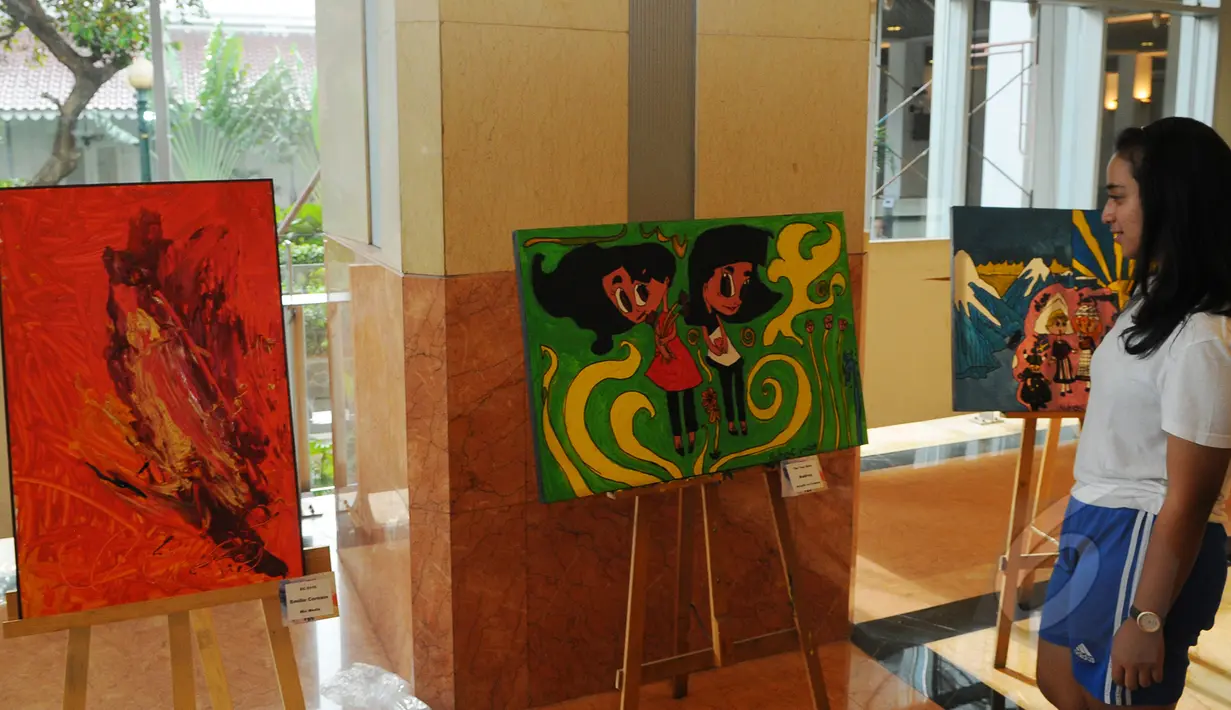 Seorang pengunjung melihat pameran lukisan hasil karya dari anak-anak autis saat acara Fun Walk for Autism 2015 bertema 'Autism Is NOT A Joke' di Balaikota DKI Jakarta, Minggu (29/3/2015). (Liputan6.com/Herman Zakharia)