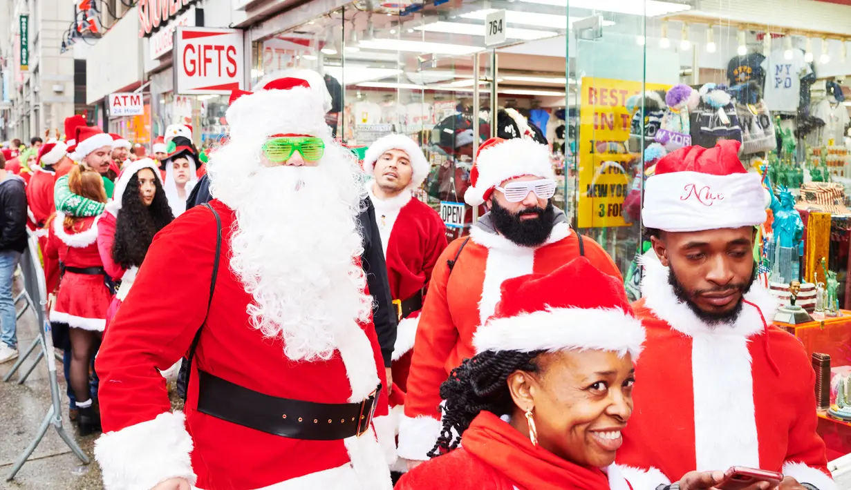 Orang-orang yang berpakaian seperti Sinterklas mengantre untuk memasuki bar dalam acara tahunan Santacon di New York City, Sabtu (14/12/2019). Dalam acara tersebut, peserta berkeliling bar untuk menyambut datangnya liburan Natal. (Gabby Jones/Getty Images/AFP)