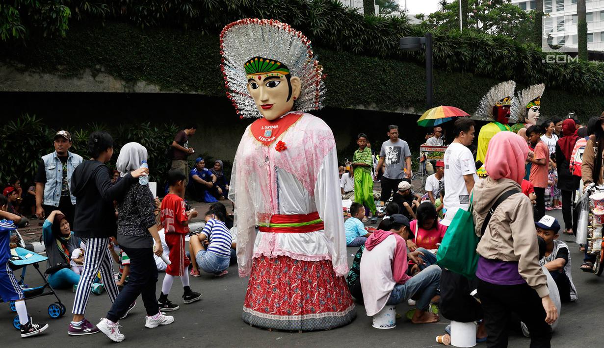 Boneka ondel-ondel berdiri diantara warga yang sedang beraktivitas di lokasi car free day, Jakarta, Minggu (21/5). (Liputan6.com/Immanuel Antonius)