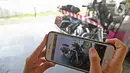 Layar ponsel mengambil gambar motor Harley Davidson milik tersangka Jiwasraya yang terparkir di Kejaksaan Agung, Kamis (16/1/2020). Kejagung menyita kendaraan dari tersangka dugaan korupsi Jiwasraya berupa enam mobil berbagai merk dan motor Harley Davidson. (Liputan6.com/Herman Zakharia)