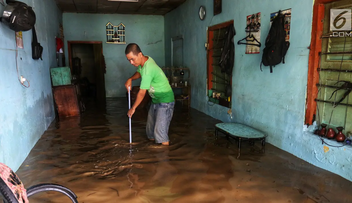 Warga membersihka rumahnya yang terendam banjir di kawasan bantaran kali Cisadane, Tangerang, Jumat (26/4). Banjir kiriman setinggi 2 meter sempat melanda kawasan akibat curah hujan yang tinggi di bogor membuat derasnya air mengalir jauh sampai ke tempat ini. (Liputan6.com/Johan Tallo)