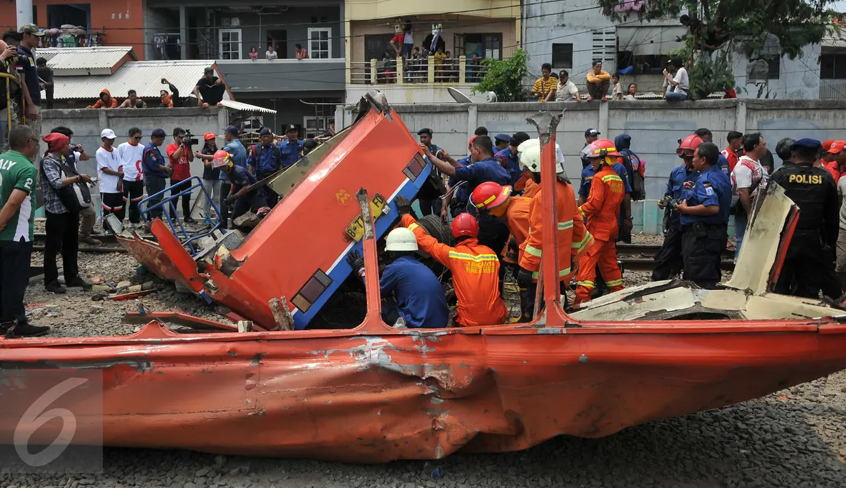 Petugas melakukan evakuasi kepada Metromini yang tertabrak kereta di perlintasan Angke, Tambora, Jakarta, Minggu (6/12/2015). Sebanyak 13 orang dilaporkan tewas. (Liputan6.com/Gempur M Surya)  