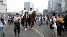 Dua pengunjung berkeliling area car free day  dengan menunggang kuda milik satuan polisi berkuda Polda Metro Jaya di Bundaran HI, Jakarta, Minggu (18/3). Kuda-kuda yang diterjunkan itu menarik perhatian pengunjung. (Liputan6.com/Faizal Fanani)