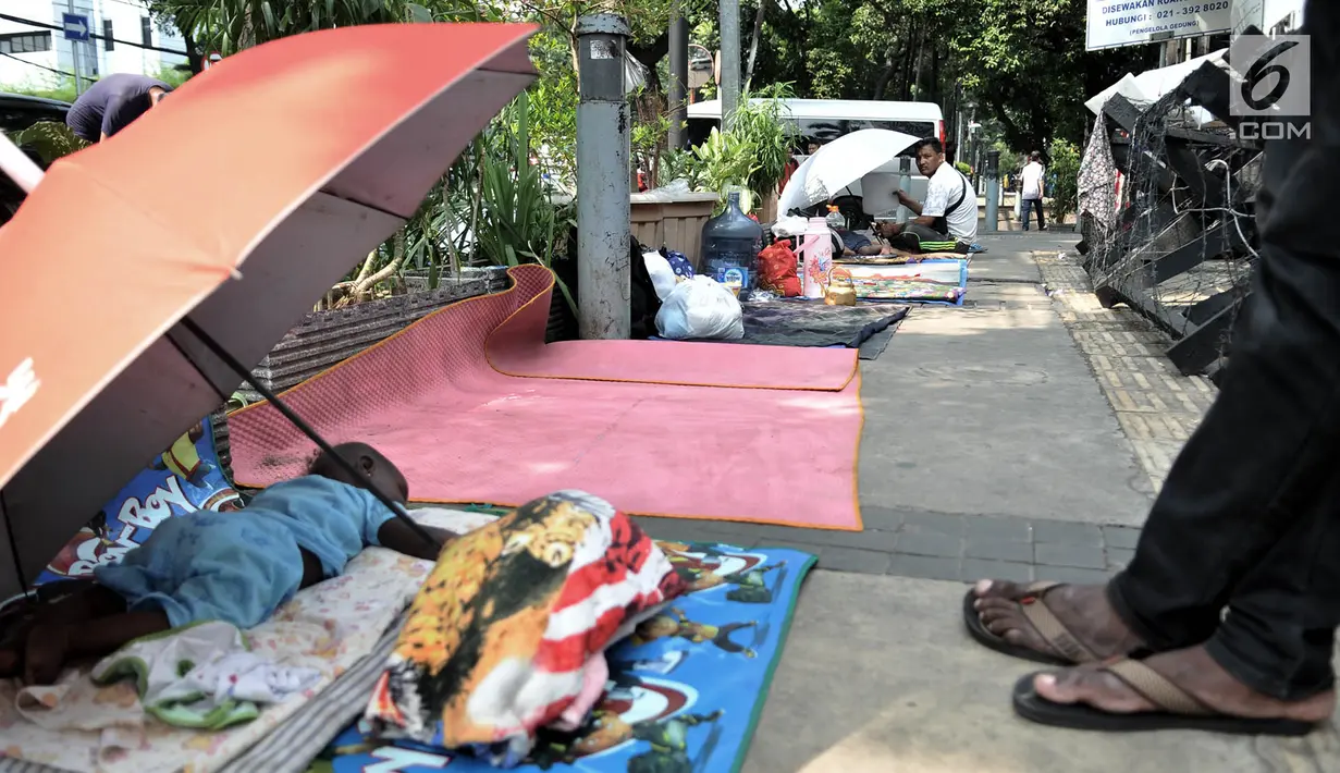 Imigran tertidur di trotoar depan Kantor UNHCR Menara Ravindo, Kebon Sirih, Jakarta, Rabu (3/7/2019). Para imigran mengaku pindah dari Rumah Detensi Imigrasi ke Kantor UNHCR lantaran tidak kunjung mendapat kabar mengenai tempat tinggal dan keputusan suaka. (merdeka.com/Iqbal Nugroho)