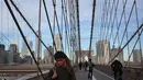 Orang-orang berjalan melintasi Jembatan Brooklyn di New York, 3 Desember 2018. Jembatan itu menjadi salah satu tujuan turis, lokasi pembuatan film maupun warga kota yang hendak menikmati suasana Brooklyn-Manhattan dari sisi berbeda. (AP/Wong Maye-E)