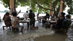 Pelanggan menyantap makanan di tengah banjir yang merendam Chaopraya Antique Café di Sungai Chao Phraya, Bangkok, Thailand, Kamis (7/10/2021). Restoran yang dilanda banjir ini menjadi tempat makan tidak biasa di mana pengunjung menikmati santapan makanan dengan kaki terendam (AP Photo/Sakchai Lalit)