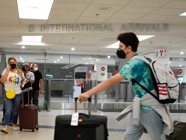 Wisatawan keluar dari pintu kedatangan Internasional di Bandara Miami, Florida, Senin (20/9/2021). Amerika Serikat akan mencabut larangan perjalanan covid-19 pada semua penumpang udara yang sudah divaksin lengkap dan menjalani tes serta pelacakan kontak pada November. (Joe Raedle/Getty Images/AFP)