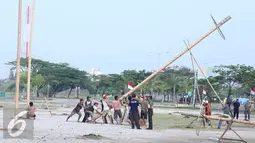 Pekerja mendirikan pohon pinang di Pantai Karnaval Ancol, Jakarta, Jumat (12/8). Taman Impian Ancol Jaya menyiapkan lomba panjat pinang kolosal dengan total pohon pinang mencapai 171 pohon. (Liputan6.com/Herman Zakharia)