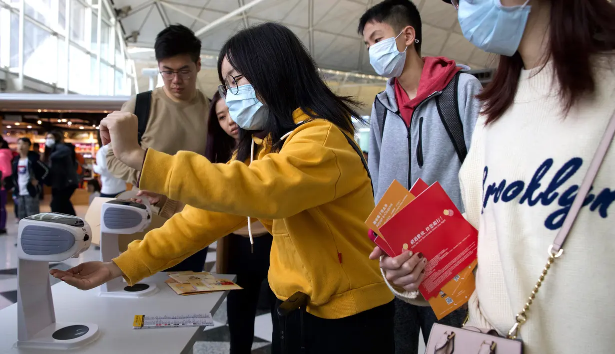 Para pelancong mengenakan masker wajah saat berada di Bandara Internasional Hong Kong di Hong Kong, Selasa (21/1/2020). Masker terjual habis dan pemeriksaan suhu di bandara dan stasiun kereta api menjadi norma baru di China menyusul merebaknya wabah virus corona.  (AP/Ng Han Guan)