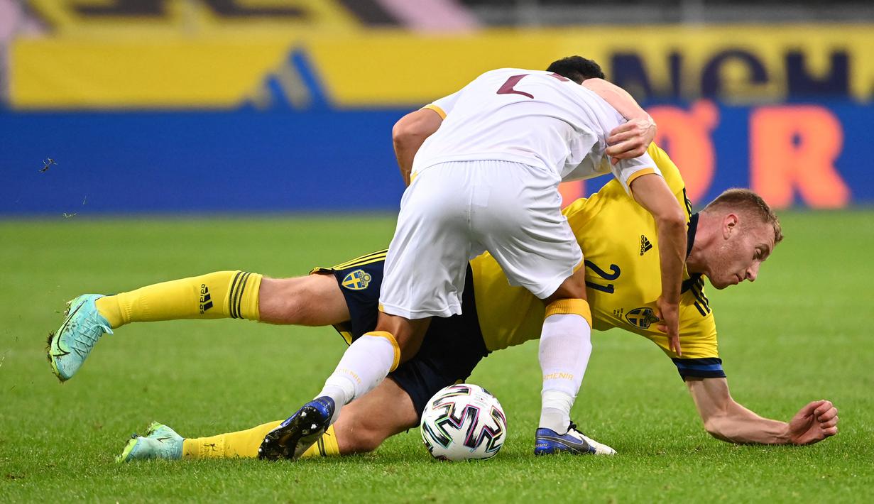 Gelandang Swedia, Dejan Kulusevski (bawah) terjatuh saat perebutan bola dengan bek Armenia, Andre Calisir dalam laga uji coba menjelang berlangsungnya Euro 2020 di Solna, Sabtu (5/6/2021). Swedia menang 3-1 atas Armenia. (AFP/Jonathan Nackstrand)