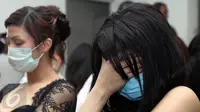 Seorang perempuan WNA menutup wajahnya saat diamankan di Kantor Imigrasi Kelas I Khusus Jakarta Barat, Sabtu (7/1). Mereka diduga melanggar keimigrasian yang berprofesi sebagai penari, pemandu lagu, Pekerja Seks Komersil (PSK). (Liputan6.com/Johan Tallo)