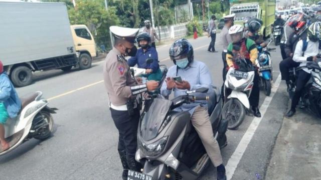 Petugas saat melakukan pemeriksaan kartu vaksin terhadap pengendara motor di Jalan Trans Sulawesi (Arfandi Ibrahim/Liputan6.com)