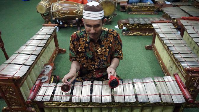 Rasino penyandang tuna netra yang menjadi guru gamelan di SMKN 8 Surakarta sedang memainkan instrumen gender.(Liputan6.com/Fajar Abrori)