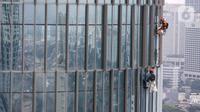 Pekerja membersihkan kaca gedung bertingkat di Jakarta, Jumat (26/02/2021). Berdasarkan data BP Jamsostek kasus kecelakaan kerja di Indonesia menurun 1,46 persen dengan catatan pada tahun 2020 mencapai 153.044 kasus dibandingkan 2019 sebanyak 155.327 kasus. (Liputan6.com/Fery Pradolo)