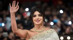 Aktris Priyanka Chopra menyapa penggemarnya saat tiba menghadiri Festival Film Internasional Marrakech ke-18 di Jemaa El Fnaa, Marrakech (5/12/2019). Priyanka Chopra tampil cantik memesona mengenakan busana sari emas dan brokat perak denga dengan kalung emas di lehernya. (AFP/Fadel Senna)