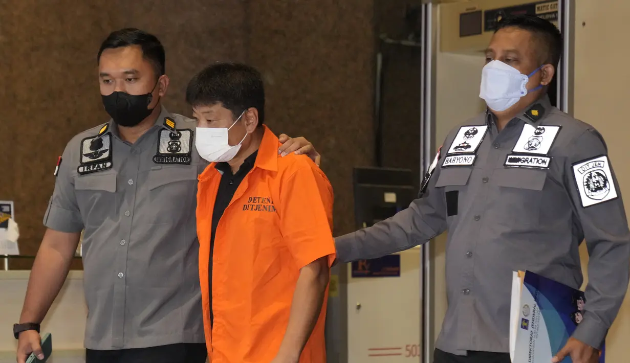 Petugas Imigrasi Indonesia mengawal buronan Jepang Mitsuhiro Taniguchi yang ditangkap di pulau Sumatera pada awal Juni, sebelum dideportasi di Jakarta, Rabu (22/6/2022). Mitsuhiro Taniguchi dipulangkan menggunakan pesawat Japan Airlines JL720 yang berangkat dari Bandara Soekarno Hatta menuju Narita Jepang pukul 06.35 WIB. (AP Photo/Dita Alangkara)
